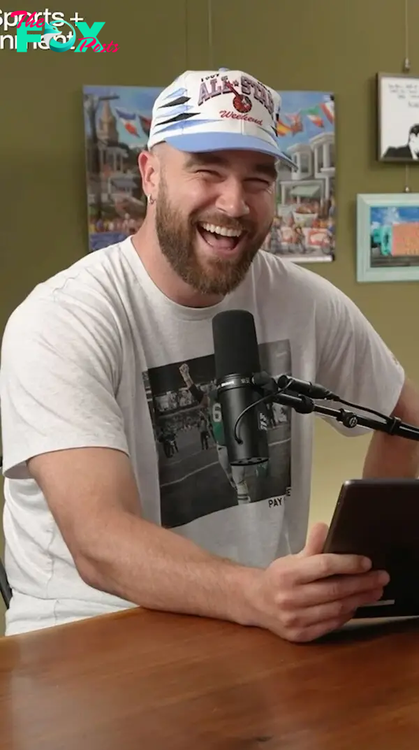 travis kelce smiling in front of a microphone