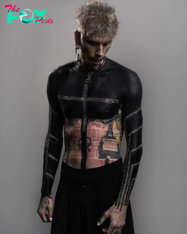 Machine Gun Kelly shows off new black out tattoos covering arms, torso.