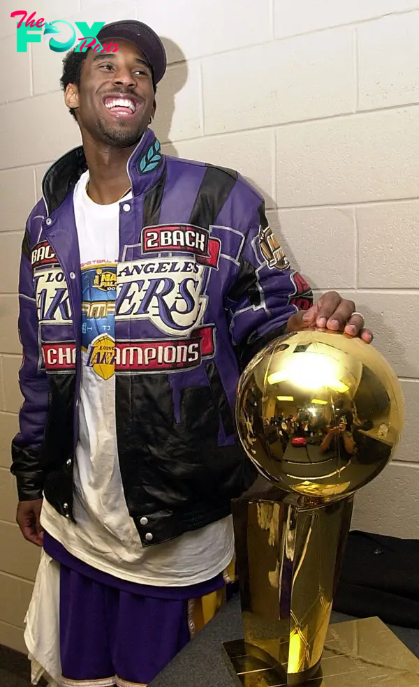 Kobe Bryant standing with the 2001 NBA Championship trophy.