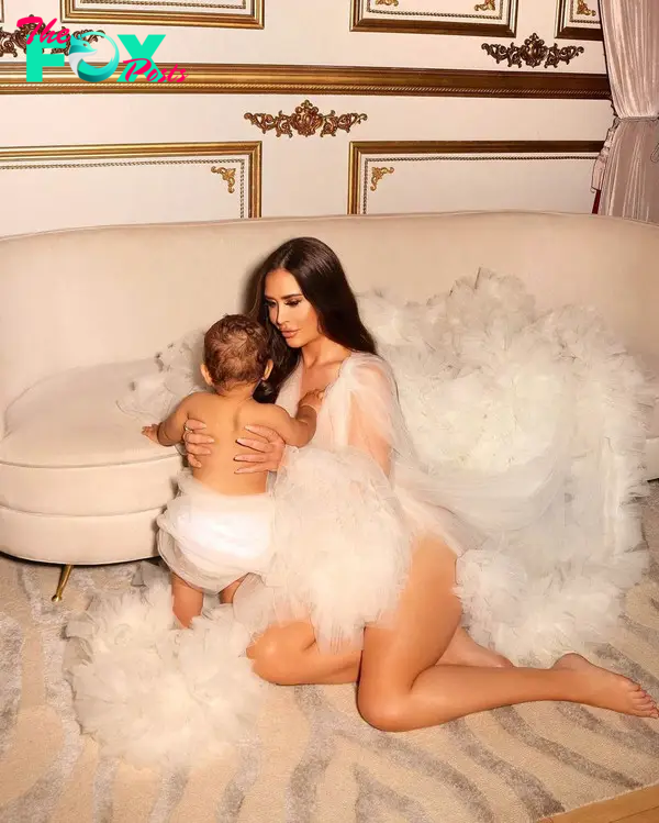 maralee nichols clad in a massive gown holding her son up