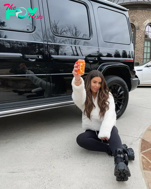 Brielle Biermann toasting a drink in front of her car.