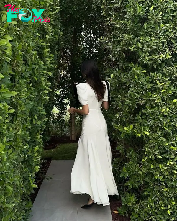 Kendall Jenner in white silk dress with back turned to camera.