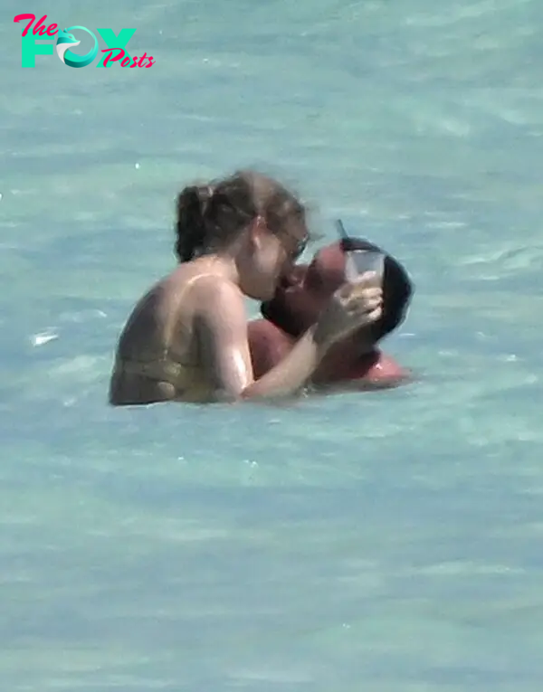 Taylor Swift and Travis Kelce kissing in the ocean.