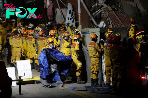 Firefighters prepare to move victims’ bodies outside a collapsed building during a rescue operation