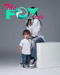This may contain: a woman sitting on top of a white box next to a little boy in jeans