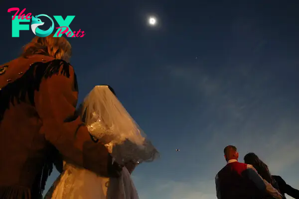 Couples view the solar eclipse during totality at a mass wedding at the Total Eclipse of the Heart festival in Russellville, Ark.