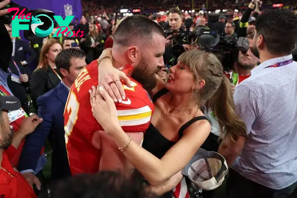 Travis Kelce and Taylor Swift hugging at a football field after a game.