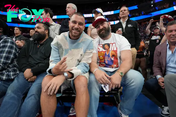 Travis Kelce and Jason Kelce sitting courtside at a game.
