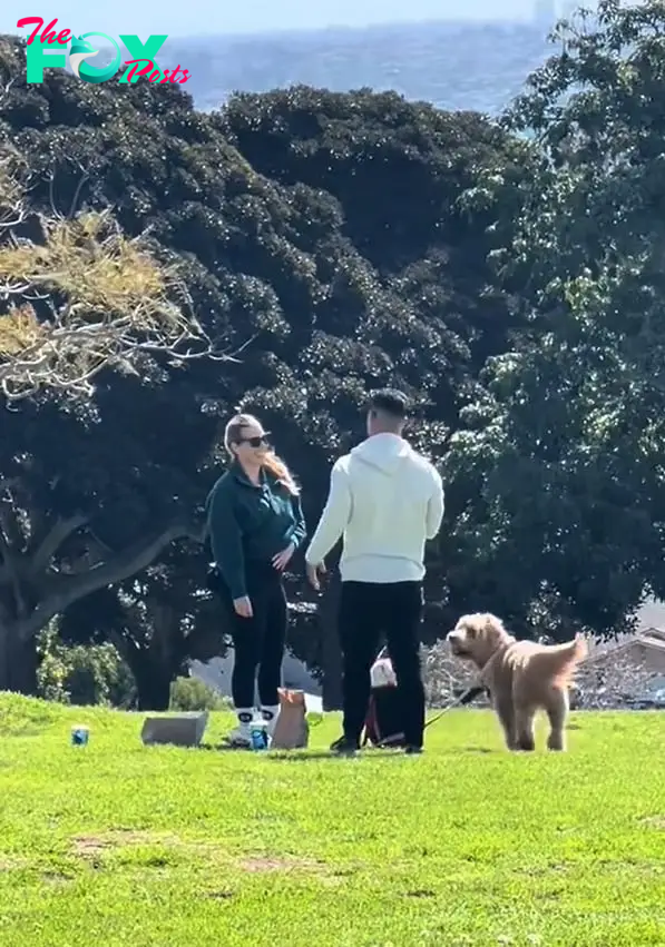 man standing with woman and dog in the park
