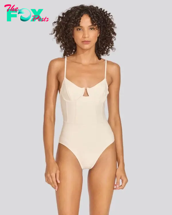 A model in a cream colored one-piece bathing suit