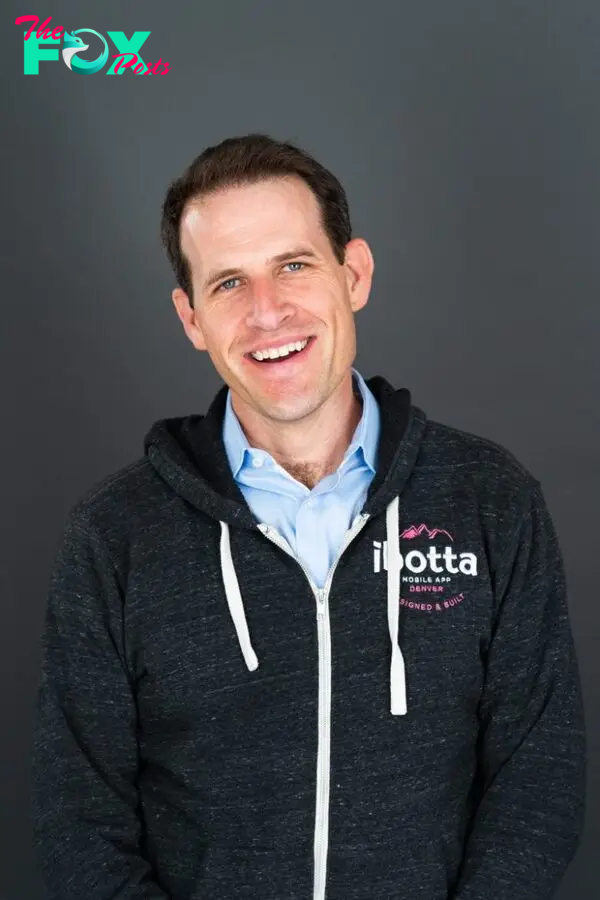 A man in a zip-up jacket that says "Ibotta" poses for a photo