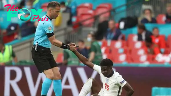 Referee Danny Makkelie helps England&#039;s Bukayo Saka during the match against Germany in the round of 16.  