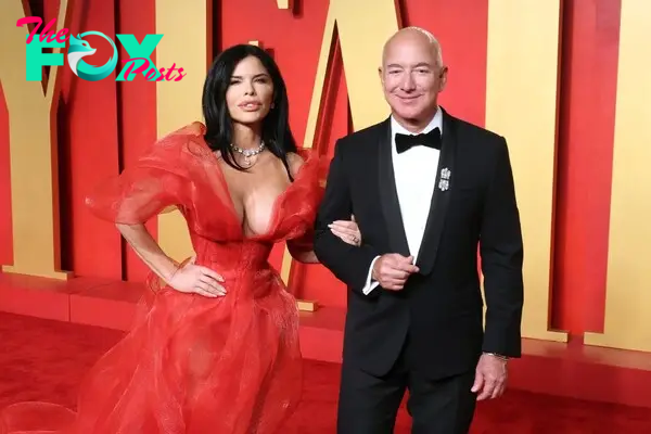 Lauren Sanchez, in red dress, links arms with Jeff Bezos, in a tuxedo.