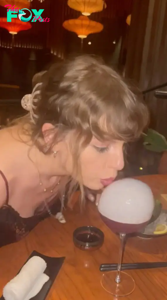 Taylor Swift blowing out a bubble on a drink.
