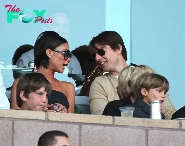 Victoria Beckham talks to Tom Cruise, as Romeo Beckham sits on his grandma Sandra Beckham's lap.