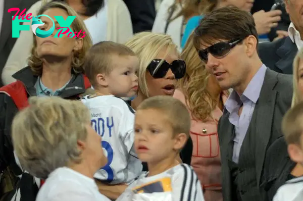 Tom Cruise talks to Victoria Beckham - holding Cruz Beckham. Sandra Beckham holds Romeo Beckham.