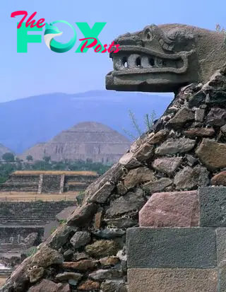 A photo of a pyramid with a stone-made serpent-like head. Another pyramid is in the background.