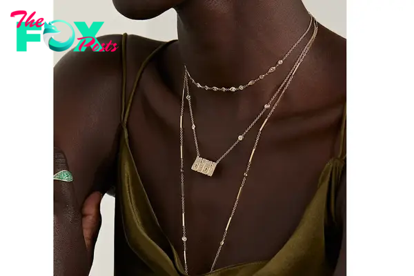 A model wearing several god and diamond necklaces, including one that spells out Mama