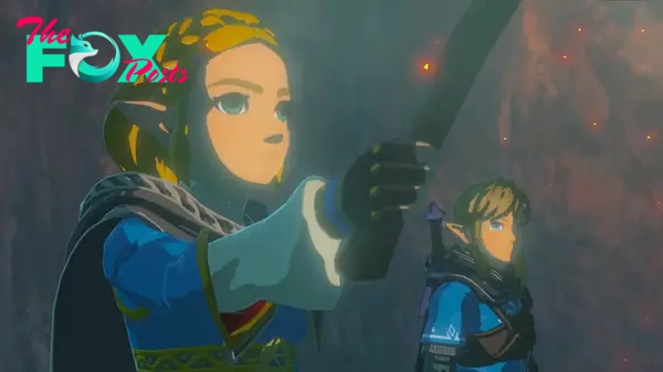Zelda holds a torch as she and Link look at something in Tears of the Kingdom