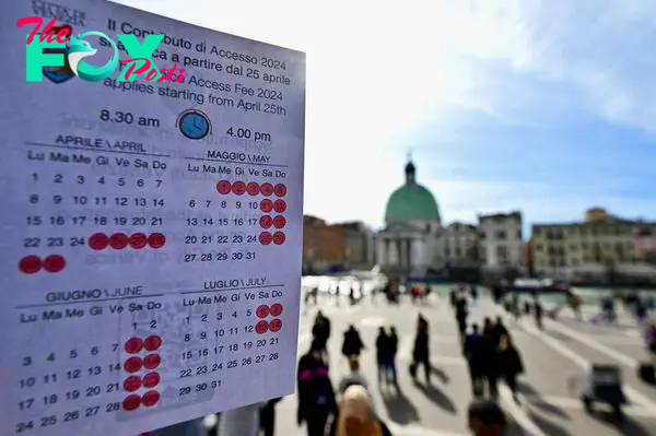 A person shows a calendar of the paying days to visit Venice, on April 19, 2024 in front of Santa Lucia train station in Venice.
