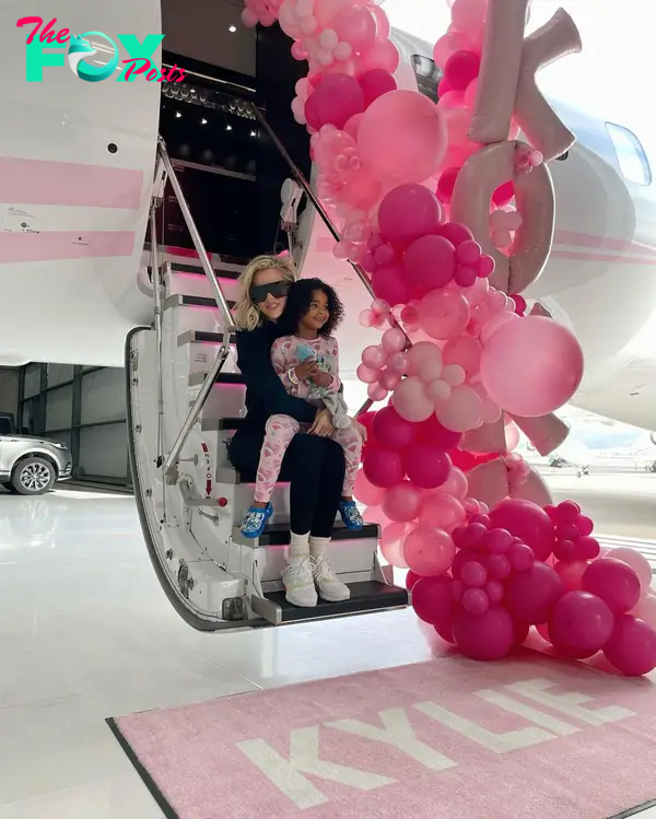 Khloé Kardashian and her daughter True Thompson sitting on a plane steps