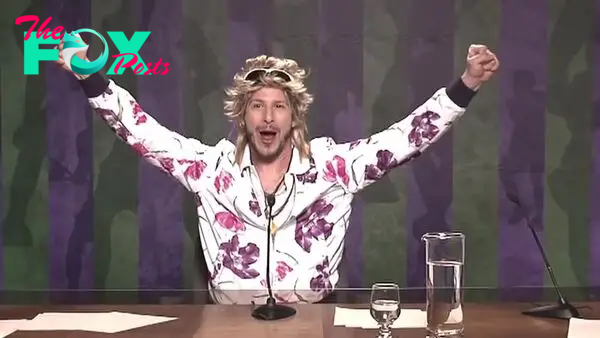 Andy Samberg raises his arms in victory in a loud jacket in 7 Days in Hell