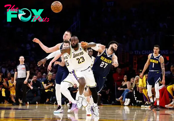 LeBron James #23 of the Los Angeles Lakers steals the ball in front of Nikola Jokic #15 and Jamal Murray #27 of the Denver Nuggets 