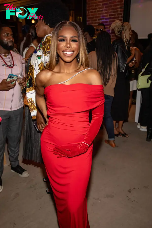 Candiace Dillard-Bassett posing in a red dress while pregnant