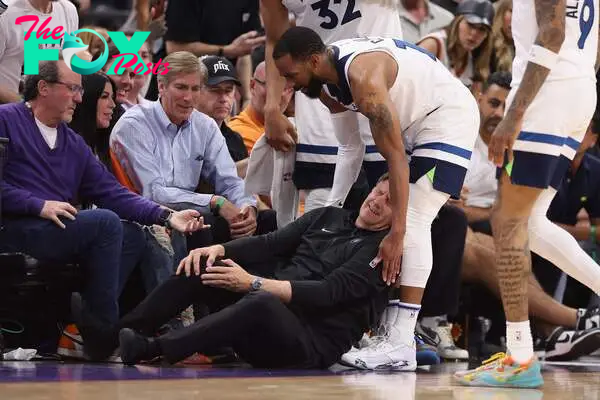 Head coach Chris Finch of the Minnesota Timberwolves grabs in leg in pain after a collision with Mike Conley #10 during the second half of game four