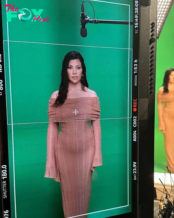 Kourtney Kardashian standing in front of a green screen.