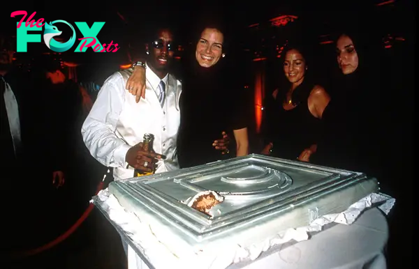 Diddy posing with Angie Harmon and his cake at the party.