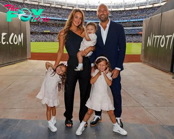 derek and hannah jeter with three of their kids at a baseball field