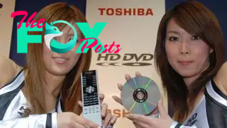 Two women hold up a DVD and remote to promote an HD DVD.