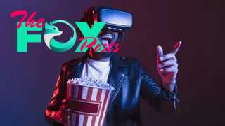 A man wears a VR headset while holding a bag of popcorn.