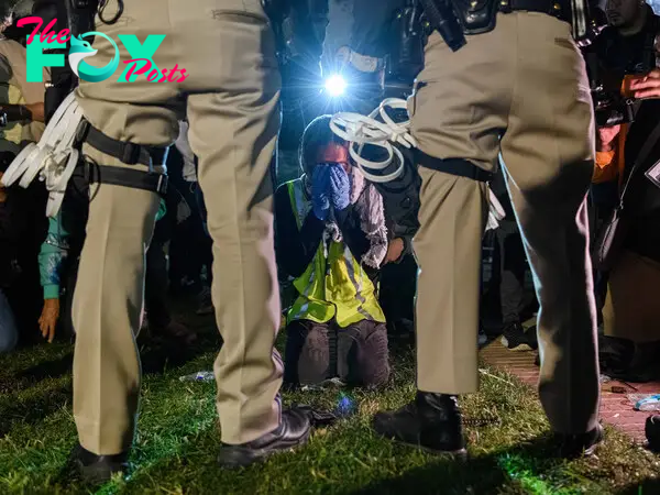 A pro-Palestinian protester kneels in front of two California Highway Patrol officers in Los Angeles on May 1.