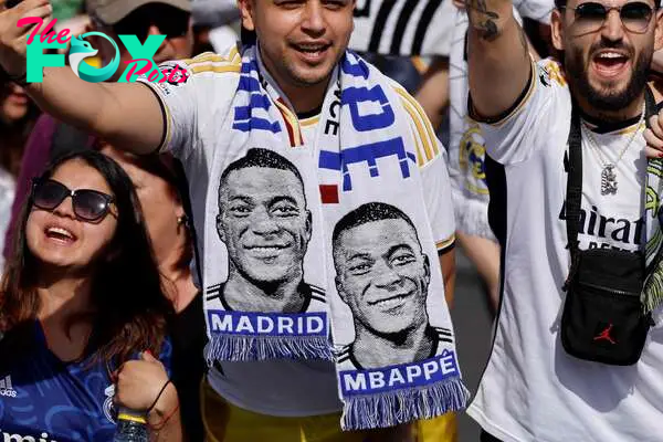 Supporters wearing football scarves depicting French footballer Kylian Mbappe cheer prior Real Madrid's celebration