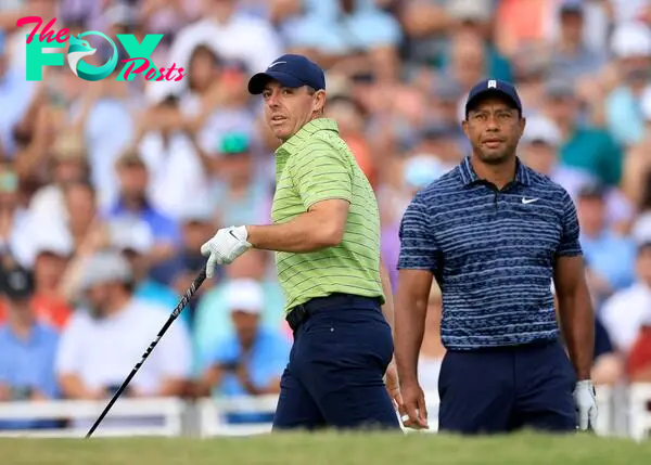 (FILES) In this file photo taken on May 18, 2022 Rory McIlroy of Northern Ireland plays his opening tee shot watched by his playing partner Tiger Woods of The United States on the 10th hole during the first round of the 2022 PGA Championship at Southern Hills Country Club in Tulsa, Oklahoma. - Tiger Woods, battling back from severe leg injuries suffered in a 2021 car crash, will join Rory McIlroy in a 12-hole December exhibition under the lights against Justin Thomas and Jordan Spieth. (Photo by DAVID CANNON / David Cannon Collection / AFP)