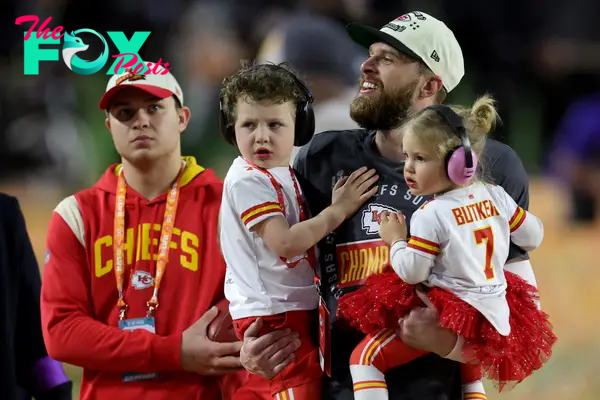 harrison butker holding his kids on the football field