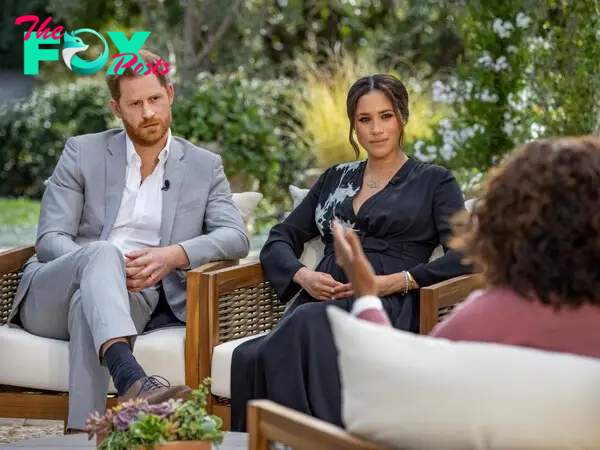 Meghan Markle and Prince Harry sitting in wicker chairs facing Oprah Winfrey who can be seen from behind