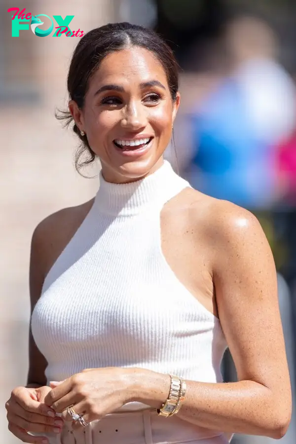 Megan Markle in a halter top wearing a watch and bracelet.