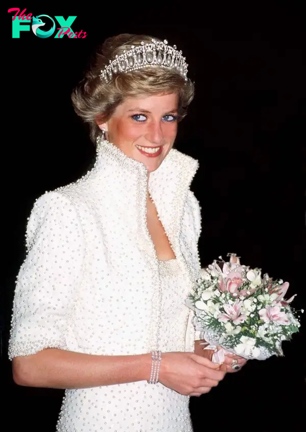 Diana holding a bouquet of flowers, wearing a white high-collar bolero over a white dress. She is smiling, has shorter hair and the Lover's Knot tiara.