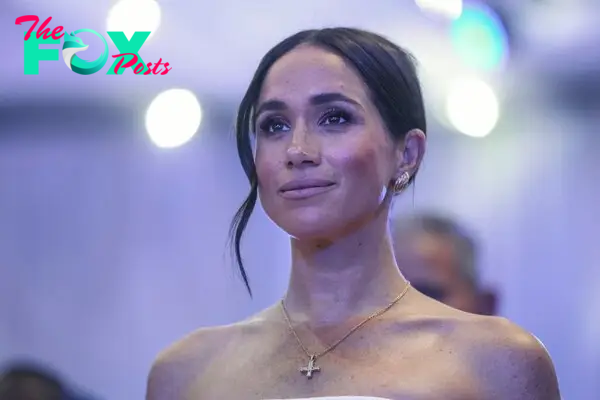 Meghan Markle with bare shoulders wearing a cross and earrings.