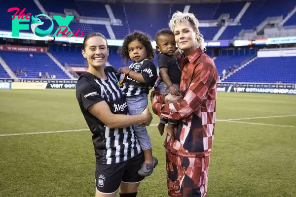 Ali Kreiger and Ashlyn Harris with their two children on the soccer field.