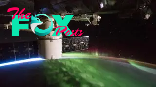 A photograph of a magenta and green aurora captured from the international space station