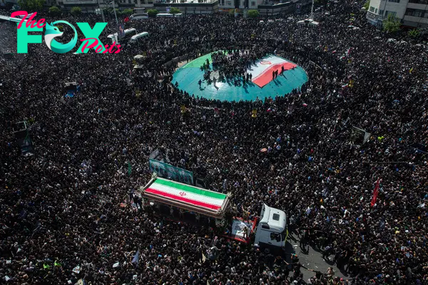 A truck carrying the coffins of President Ebrahim Raisi, Foreign Minister Hossein Amir Abdollahian and others is driven through a throng of mourners during a funeral procession in Tehran on May 22, 2024.