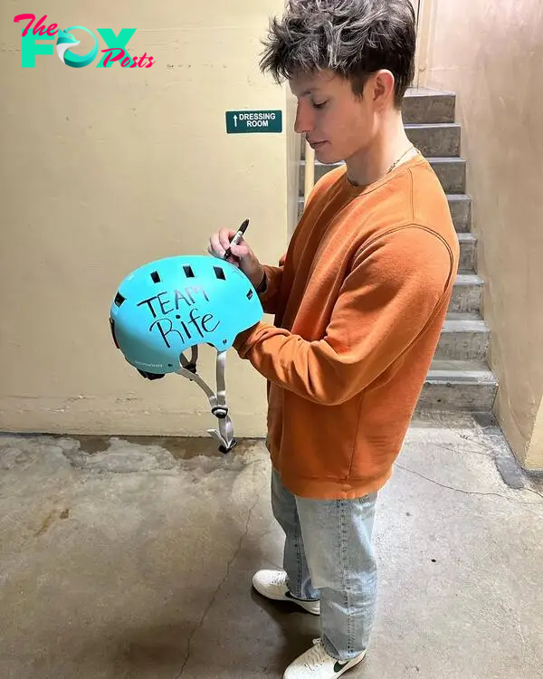 Matt Rife signing a special needs helmet.