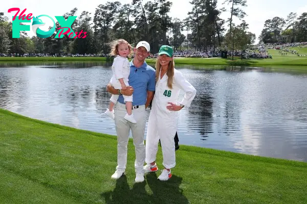 rory mcilroy posing on the golf course with Erica Stoll and daughter Poppy McIlroy