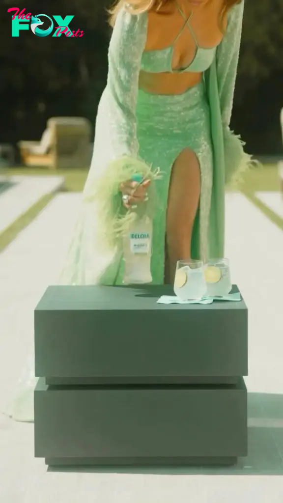 Jennifer Lopez wears green sequin and feather look in Delola Light Margarita ad.