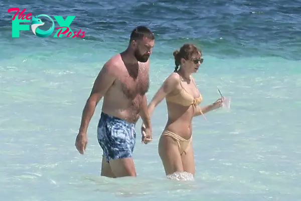 Travis Kelce and Taylor Swift holding hands in the ocean