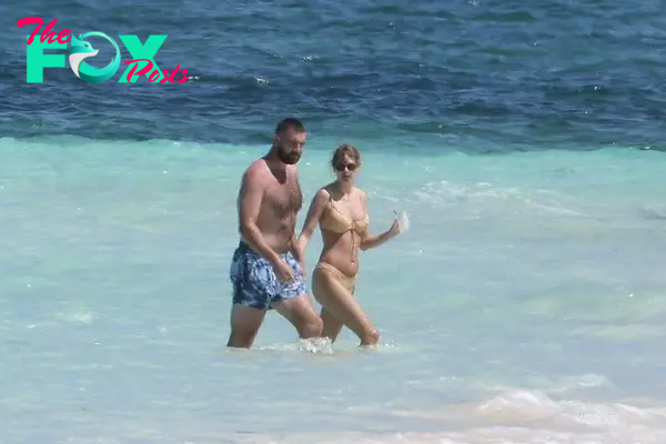 Travis Kelce and Taylor Swift holding hands in the ocean